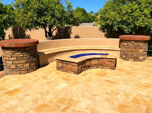 a photo by san tan valley landscaping -- a hardscaped backyard with a bench and half-circle shaped fireplace in front of the bench